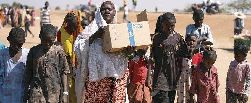 スーダンでの戦闘から逃れ南スーダンに到着し食料を運ぶ家族