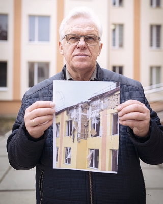 砲撃された建物の写真を手にするザフリュパニさん。
